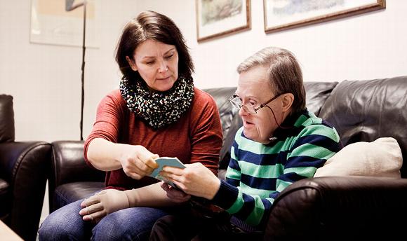 care worker with older man sitting on sofa